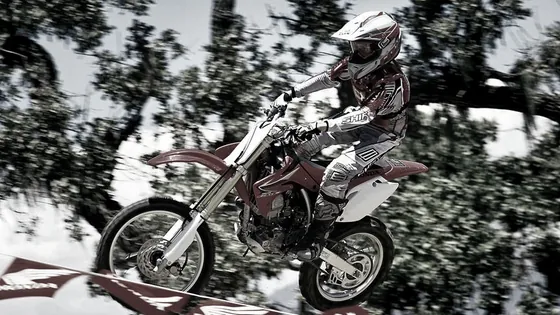 Jugendlicher springt mit der Jugend Motocross Honda CRF150R über eine Kuppe