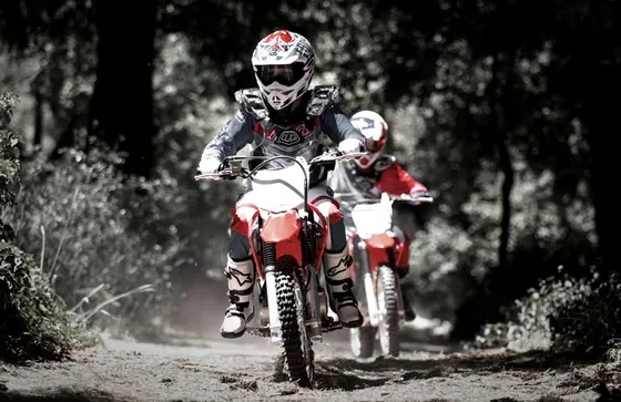 Zwei junge Fahrer auf der Kinder Motocross Honda CRF125F auf einem Waldweg